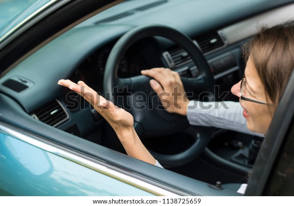 A female\
driver is nervous sitting in the car. The woman is indignant,\
screaming from her car to someone.\
