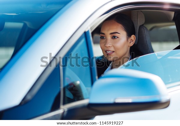 Female driver. Positive nice woman sitting in the
car while looking at the
road