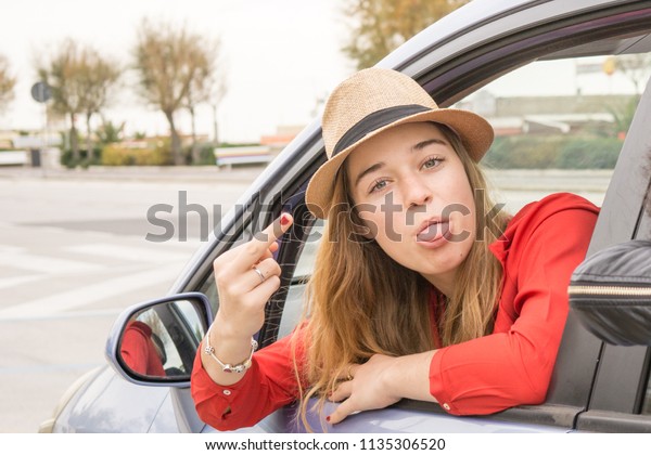 female driver showing middle finger in and obscene\
gesture or vulgarity or funny . concept of offensive gesture while\
driving car.