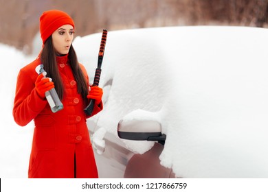 Female Driver with Snow Brush and Windshield Deicing Spray. Funny girl trying to get her car out of the snow in winter season
