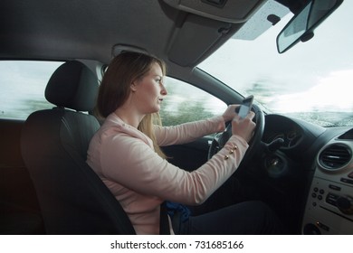 Conductora femenina que usa el teléfono celular para enviar mensajes de texto mientras conduce un auto