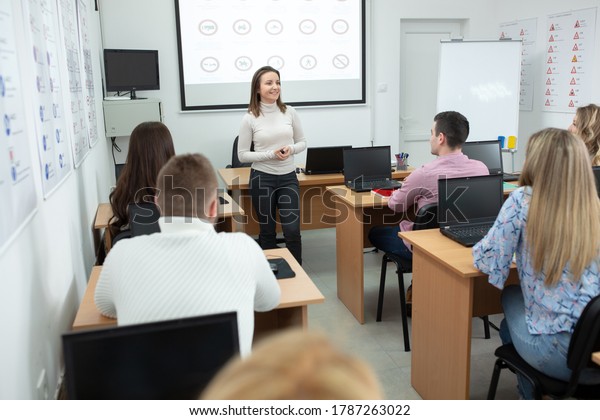 Female driving instructor explaining\
traffic signs meaning to her students in the\
classroom