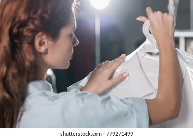 Female Dry Cleaning Worker Holding Clean Clothing In Plastic Bag