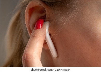 Female Ear With Bluetooth Earphone And Finger Closeup