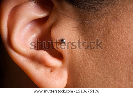 female ear tragus piercing close-up detail photo