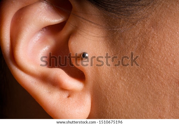 female ear\
tragus piercing close-up detail\
photo