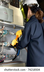 Female Electrician With Protective Clothing Performing Work In An Energized Panel. All Trade Marks Removed Or Modified.