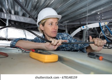 Female Electrician Working In Confined Space