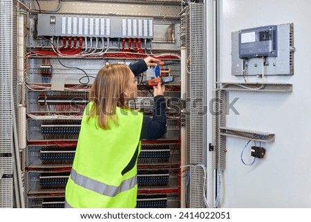 Female electrician working with voltmeter at fuse box 商業照片 © 