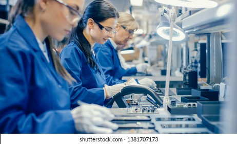 Female Electronics Factory Workers in Blue Work Coat and Protective Glasses Assembling Printed Circuit Boards for Smartphones with Tweezers. High Tech Factory with Employees. - Shutterstock ID 1381707173
