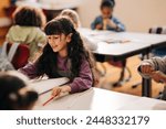 Female elementary school student sitting at her desk and doing her school work. Girl schooling in a co-ed child development centre.