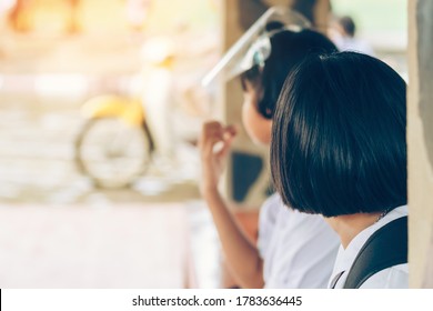 Female Elementary School Student Wear Face Mask To Prevent The Coronavirus(Covid-19) Wait For Her Parents To Pick Her Up To Return Home After School And The Rain Just Stop In Front Of The School Gate