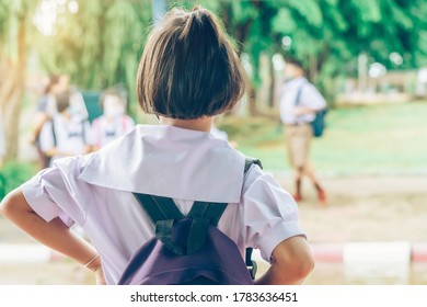 Female Elementary School Student Wear Face Mask To Prevent The Coronavirus(Covid-19) Wait For Her Parents To Pick Her Up To Return Home After School And The Rain Just Stop In Front Of The School Gate