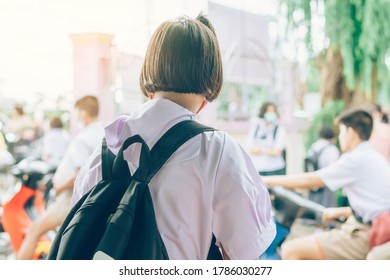 Female Elementary School Student Wear Face Mask To Prevent The Coronavirus(Covid-19) Wait For Her Parents To Pick Her Up To Return Home After School And The Rain Just Stop In Front Of The School Gate