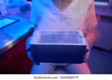 Female embryologist holding a tank for cryopreservation of biological material