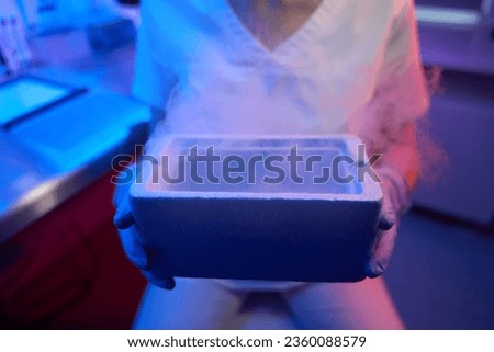 Female embryologist holding a tank for cryopreservation of biological material