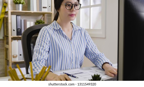 Female Employee Confident In Glasses Sit Straight At Office Desktop Using Computer Looking At Monitor Concentrated Working. Successful Woman Career Focused On Screen Checking Project Of Architecture