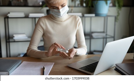 Female employee in protective face mask disinfect hands with sanitizer in office, protect from coronavirus pandemic, woman worker sanitize cleanse use antibacterial gel at workplace, covid-19 concept - Powered by Shutterstock