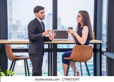 ฺBeautiful female employee wearing glasses holding a coffee cup greeted with a morning colleague at the company's cafeteria. - Powered by Shutterstock