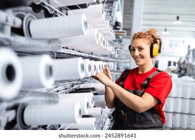 Female employee working in textile factory checking industrial sewing machine. - Powered by Shutterstock