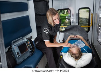 Female EMT Worker Tending To Ill Senior Patient, Listening To Heart Rate With Stethoscope