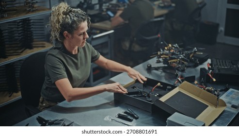 Female Engineer Assembling FPV Drone For Defense or Security Purposes. Focused Woman Meticulously Assembling Drone in Manufacturing Facility. Concept Women Role in Technology and Defense Production.