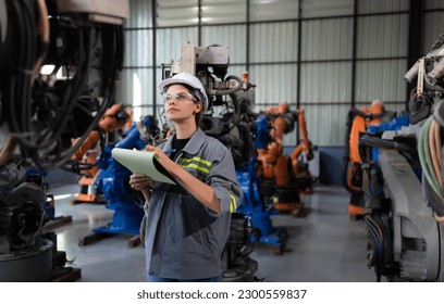 A female engineer checking documented items after installing a program on a robotic arm in a robotic warehouse and test the operation - Shutterstock ID 2300559837