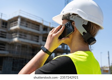 Female engineer at construction site of a building. Woman supervisor talking on the phone. Professional architect businesswoman wearing hard hat safety helmet and reflective clothing vest. - Powered by Shutterstock