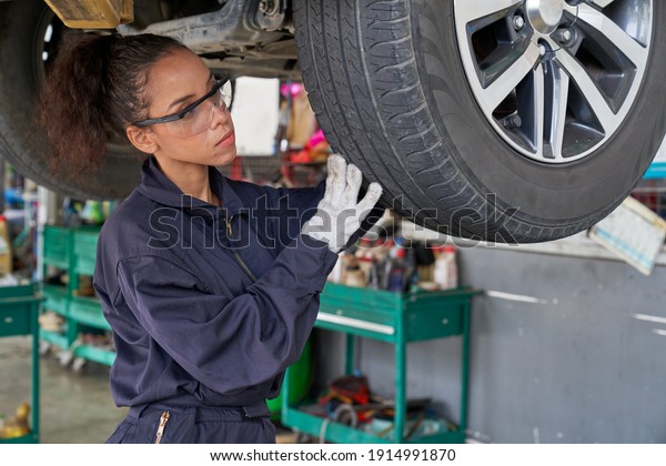 Female engineer fix or\
check tire and wheel car with hydraulic lift in car service garage\
for maintainance