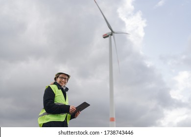 Female Engineer In Front Of Wind Turbine