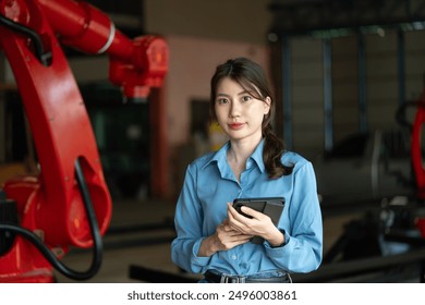 Female engineer holds a digital tablet in a robotics workshop, representing modern technology and professional focus in an industrial setting. - Powered by Shutterstock