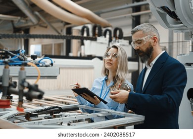 Female engineer and male project manager standing in modern industrial factory by precision robotic arm. Robot assembling wooden furniture in big furniture manufacturing facility with industrial - Powered by Shutterstock