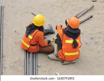 Female Engineer N Hi Vis Clothing Sitting On Ground Having A Break From Outdoor Work