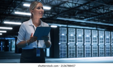 Female Engineer Programs Something while Holding Tablet Computer in Hands. She Works in a Dark Modern High-Tech Office. High-Speed Data Transfer and Smooth Server Operation, Analytics, Statistics - Powered by Shutterstock