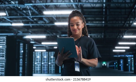 Female Engineer Programs while Holding Tablet Computer and Typing at the Screen. She Works in a Dark Modern High-Tech Office. High-Speed Data Transfer and Smooth Server Operation Concept - Powered by Shutterstock