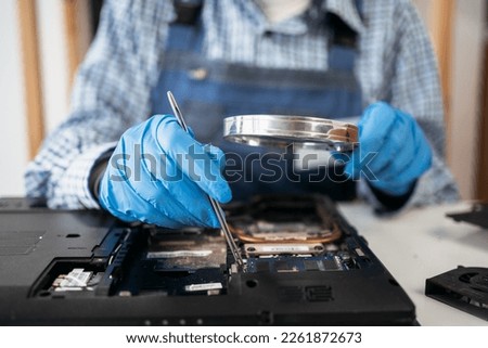 Female engineer repairing and upgrade laptop computer in service center. Worker with tools. Computer Hardware. Magnifying Glass. Disassembled laptop. Close up hands
