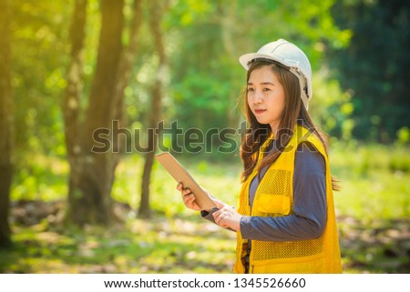 Female engineer standing confidently with white helmet and tablet in the forest, Smart and beautiful women engineer looking forword with confident- Image