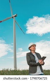 Female engineer with tablet computer on modern wind turbine farm during maintenance project planning