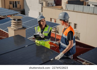 Female engineer testing urban Solar Panels with Multimeter and clipboard, man receiving instructions for maintenance of photovoltaic system. Side angle, top view, Horizontal - Powered by Shutterstock