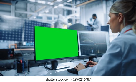 Female Engineer Uses Green Screen Computer To Analyse Satellite. Aerospace Agency Manufacturing Facility: Scientists Develop, Assemble Spacecraft For Space Exploration Mission. Over Shoulder