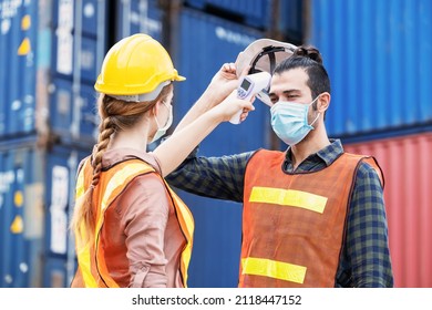 Female Engineer Worker Scanning To Check Temperature Of Staff Before Entering To The Container Construction Site By Using Digital Thermometer. Wearing Hygiene Face Mask. New Normal Concept