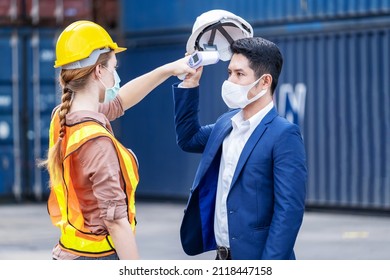 Female Engineer Worker Scanning To Check Temperature Of Staff Before Entering To The Container Construction Site By Using Digital Thermometer. Wearing Hygiene Face Mask. New Normal Concept