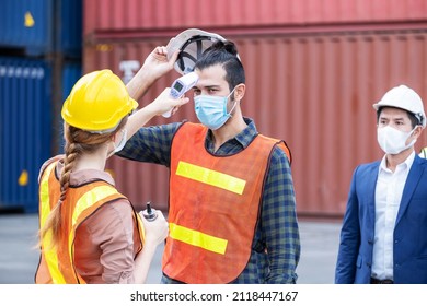 Female Engineer Worker Scanning To Check Temperature Of Staff Before Entering To The Container Construction Site By Using Digital Thermometer. Wearing Hygiene Face Mask. New Normal Concept