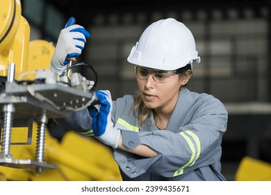 Female engineer working and checking, repair, maintenance autonomous robotics arm. Woman engineer inspecting parts of robotics arm. Engineering and robotics concept - Powered by Shutterstock