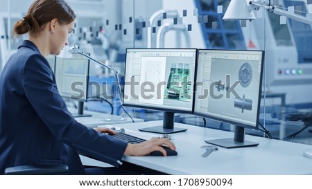 Female Engineer Working on a Personal Computer, Two Monitor Screens Show Chroma Key / Green Screen Display and CAD Software with 3D Model of Industrial Machinery Mechanism. Working Modern Factory