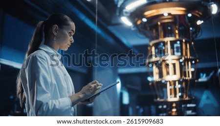 Female Engineer Working on Quantum Computer Hardware, Using Tablet Computer to Access Technical Specifications and Control Processor Parameters. Group of Developers Work on AI Behind a Desk
