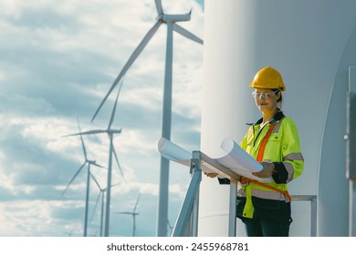 female engineer working outdoor with safety at wind turbines clean energy power station background, worker people with renewable energy technology for future concept.