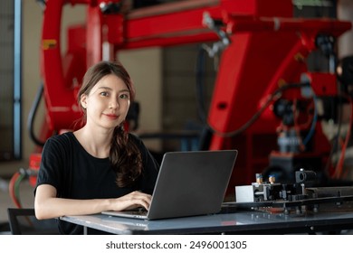 Female engineer works on her laptop in a robotics workshop, showcasing her skills and focus in a technical environment. - Powered by Shutterstock