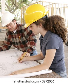 A Female Engineering Student On A Construction Site Marking Blueprints As Her Instructor Watches.