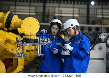 Female engineers checking AI robot training kit and mechatronics engineering in the manufacturing automation and robotics. Industrial welding robots in production line manufacturer factory.